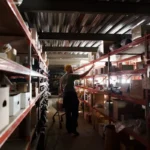 Pekerja gudang menata barang inventaris di rak penyimpanan